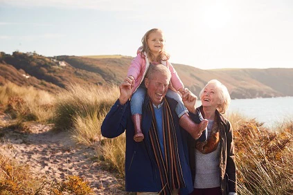 Retired Couple Walking On Cliff With Grandchild