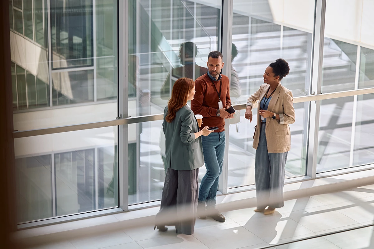 Three employees talking in an atrium