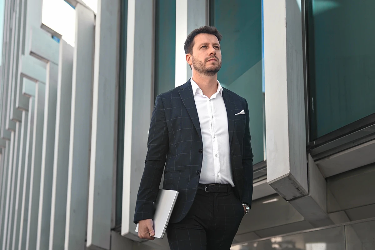 Man with laptop walking outside office