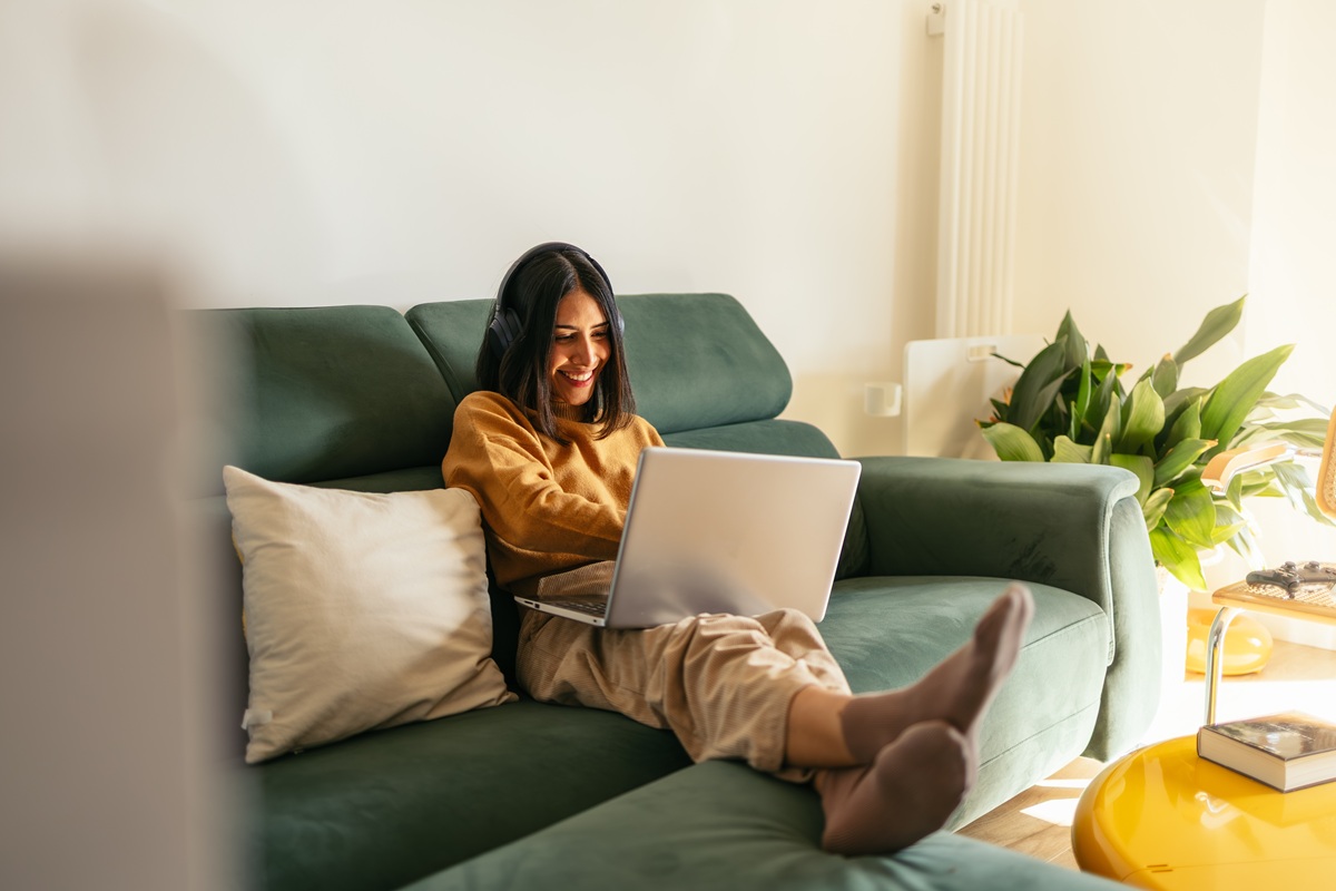 Young woman relaxing on sofa with laptop