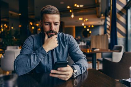 Tense-looking man checking phone in a bar