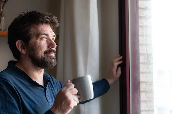 Man with coffee looking out of the window