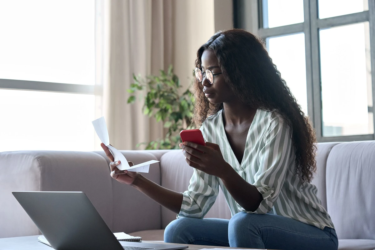 Young Woman Checking Documents On Laptop And Phone
