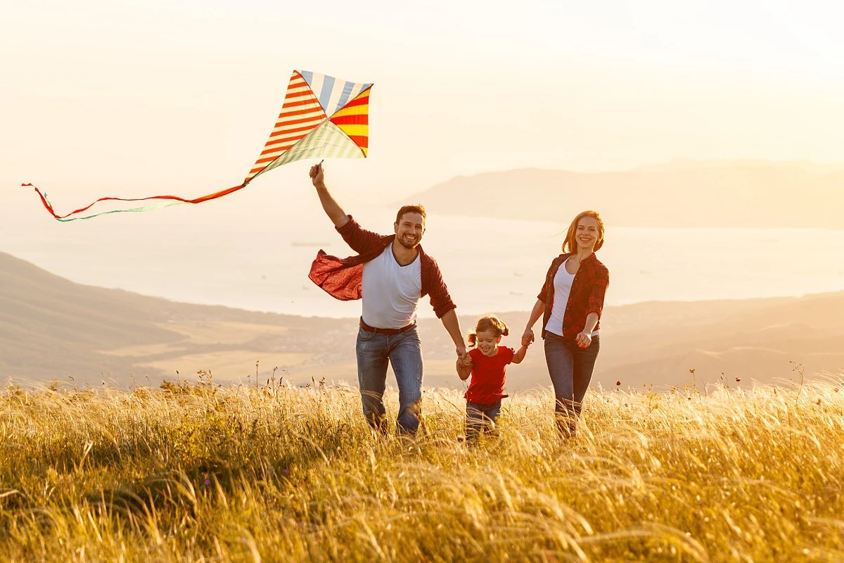 Young Couple Walking With Child And Kite