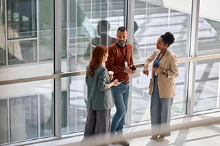 Three employees talking in an atrium