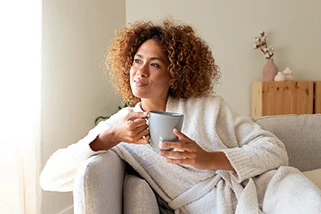 Woman sat on couch with a coffee